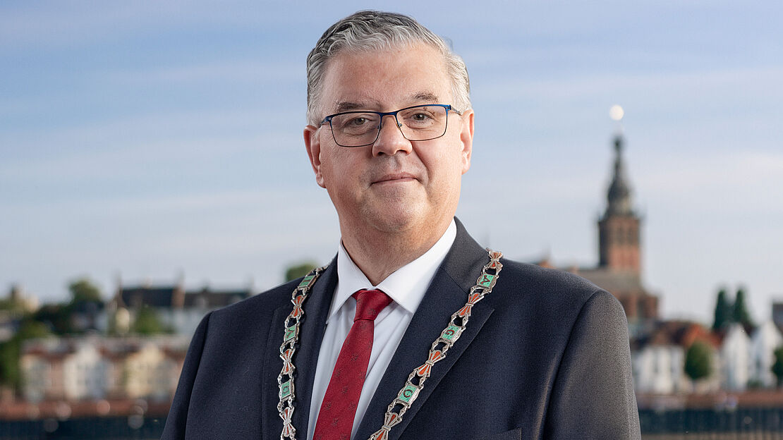 Portretfoto Burgemeester Bruls met Marikenbeeld op de achtergrond