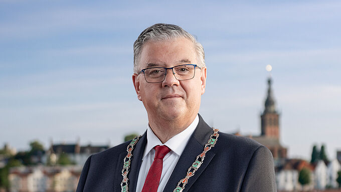 Portretfoto Burgemeester Bruls met Marikenbeeld op de achtergrond